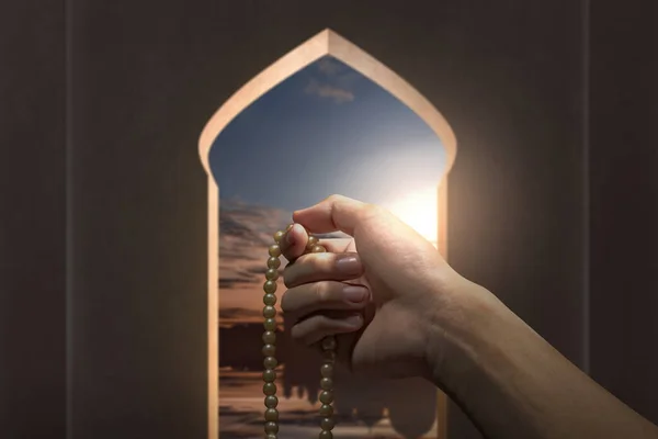 Muslim man praying with prayer beads on his hands inside the mosque