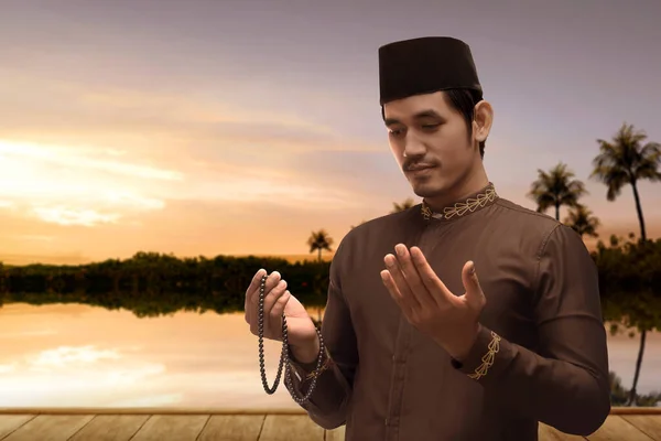 亚洲穆斯林男子双手拿着祈祷珠子 背景是夕阳西下的天空 — 图库照片