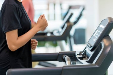 Spor salonunda koşu bandında egzersiz yapan bir kadın.
