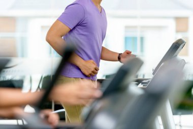 Spor salonunda koşu bandında egzersiz yapan bir adam.