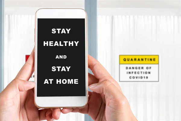 携帯電話を持っている手は 健康を維持し 画面上の自宅に滞在するためのメッセージを持ちます インフルエンザの予防 コロナウイルス — ストック写真