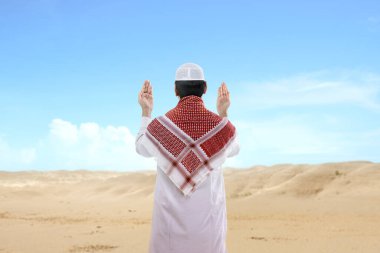 Asyalı Müslüman adamın dikiz aynasından el kaldırarak mavi bir arkaplan ile dua edişinin.