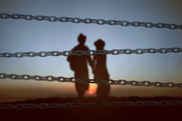 朝に立ってカップルのシルエットとチェーンフェンス 世界難民の日のコンセプト — ストック写真