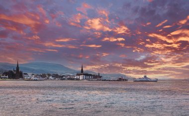 Ayrshire 'daki rıhtımda yerel feribot iskelesi. Paddle vapuru gün batımında alevli kırmızı gökyüzü ile arka planda görülebilir..
