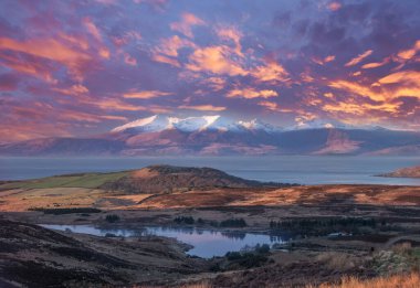 Güneş batarken Dalry Moor Yolu 'ndan Fairlie' ye bakan Arran Adası..