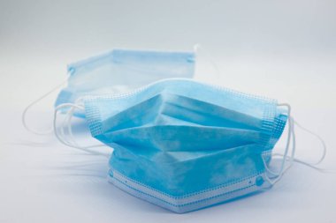 Tıbbi yüz maskeleri, Covid-19 Corona virüsünün yayılmasını engellemek amacıyla birçok ülkede kamu kullanımı için önerilen temel kişisel koruma ekipmanlarını maskelemektedir. Beyaz arkaplanda.