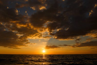 Gün batımında deniz manzarası. Nimbus bulutları turuncu gökyüzünü düşük ışıkta gösteriyor..