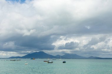 Dağ manzaralı sahil manzarası ve yağmur mevsiminde kara bulutlar.