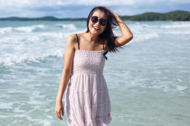 Ayakta duran ve sahilde eğlenen kadın