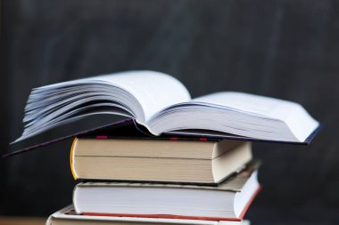 Kitap yığını kapat kara tahta arka plan ile. Bir kitap 