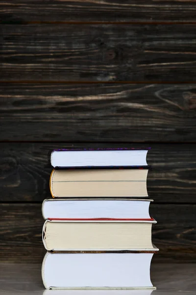 Bücherstapel mit dunklem Holzhintergrund. vertikale Orientierung — Stockfoto