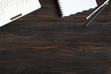 Laptop, defter ve kalemler banın koyu ahşap zemin üzerine