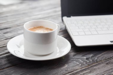 Kahve fincanı yakın up ve dizüstü bilgisayar gibi arka plan rustik ahşap ta