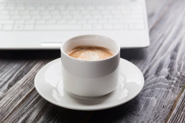 Kahve fincanı yakın up ve koyu ahşap masa üstünde laptop