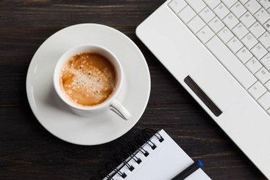 Kahve fincanı, dizüstü bilgisayar ve ahşap masa üstünde not etmek. Üstten Görünüm