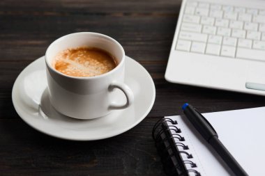 Kahve fincanı, dizüstü bilgisayar ve ahşap masa üstünde not etmek. 