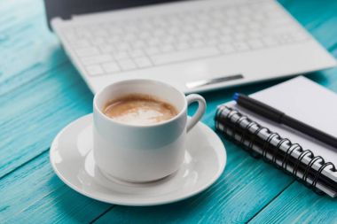 Kahve fincanı, defter ve laptop üzerinde ahşap turkuaz backgrou