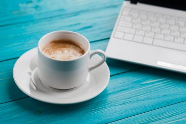 Kahve fincanı ve turkuaz ahşap arka plan üstünde laptop