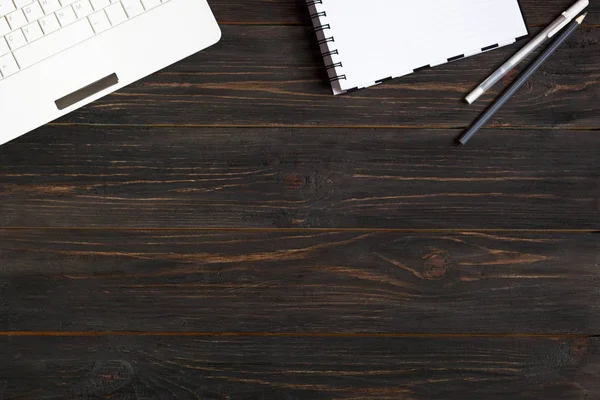 Laptop, defter ve kalemler banın koyu ahşap zemin üzerine