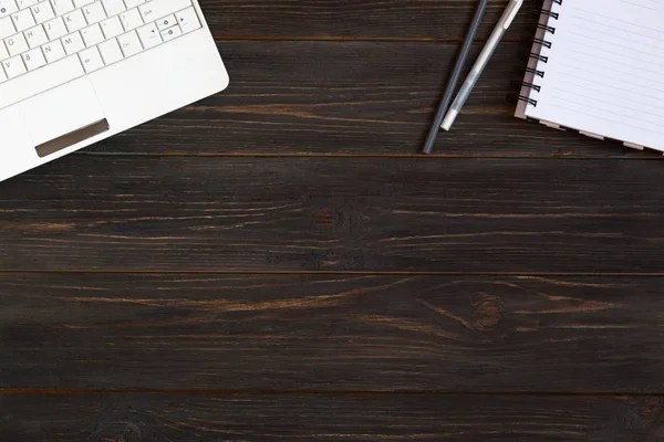 Laptop, defter ve kalemler koyu ahşap zemin üzerinde. Yer fo