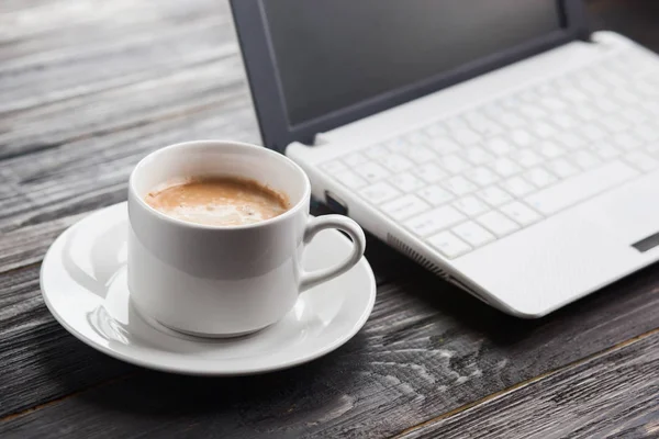 Kahve fincanı ve laptop ahşap masada.