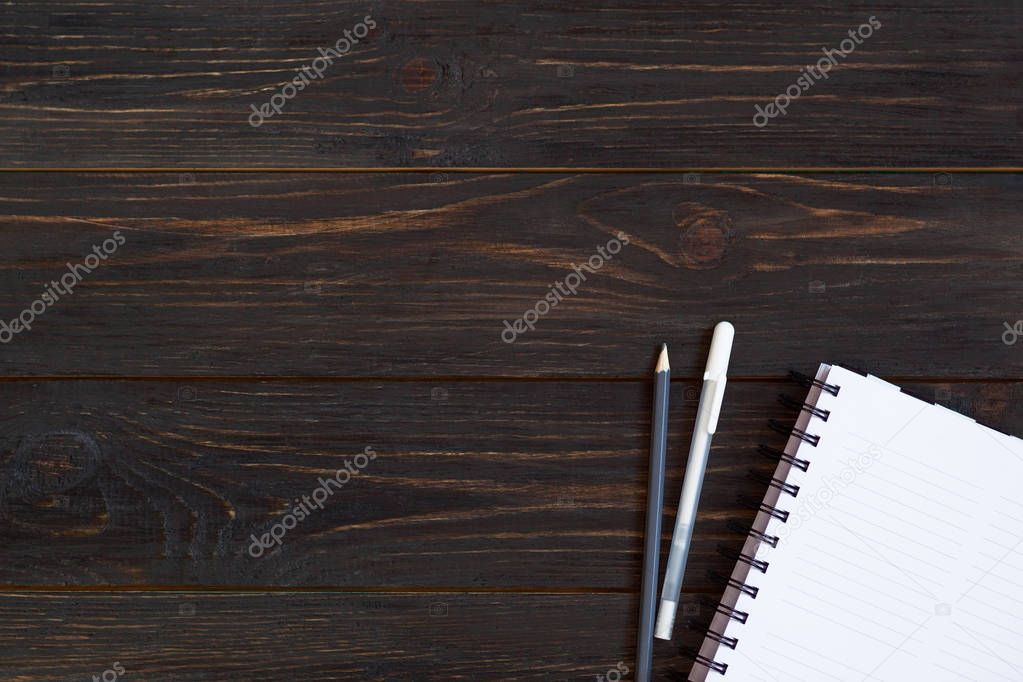 Notebook and pencils on dark wooden background with place for te