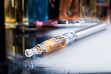 Arka planda e-sıvı şişe ile elektronik sigara
