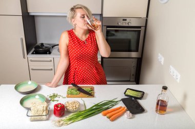 Genç kadın kitche içinde pişirme sırasında viski bardaktan içiyor