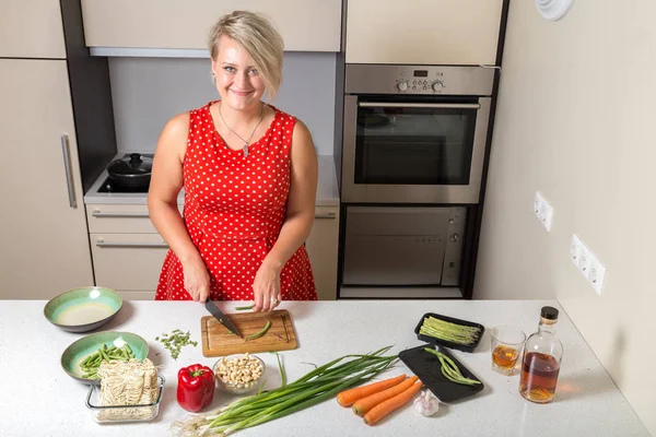 Gülümseyen ve kuşkonmaz mutfakta kesme genç kadın