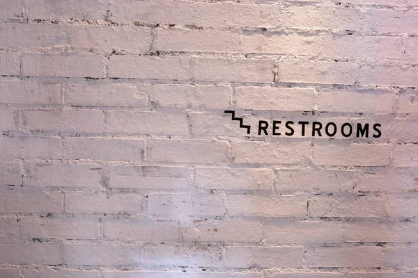 Restroom sign on a white brick wall — Stock Photo, Image