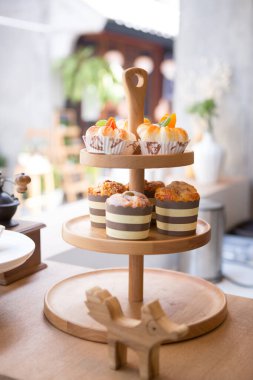 Üç katlı ahşap pasta standı ve kaldırım kafeteryasındaki tezgahın üzerine biraz tatlı.
