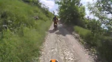 Motosikletliler dağlarda çakıllı bir yolda gezerler. Moto motorcu kayalık bir yolda motosiklet sürüyor.. 