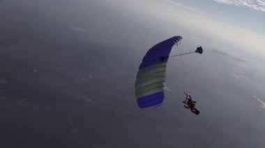 Skydiver pilotları paraşütünü gökyüzünde bulutların arasında uçuruyor..