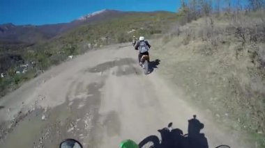 Motosikletliler dağlarda çakıllı bir yolda gezerler. Moto motorcu kayalık bir yolda motosiklet sürüyor.. 
