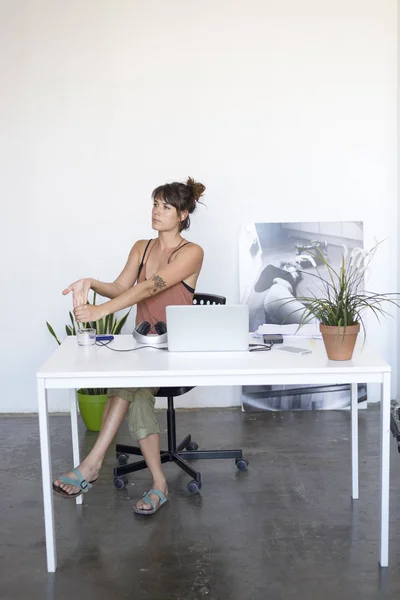 Empresaria sentada a la mesa en oficina y estirándose — Foto de Stock