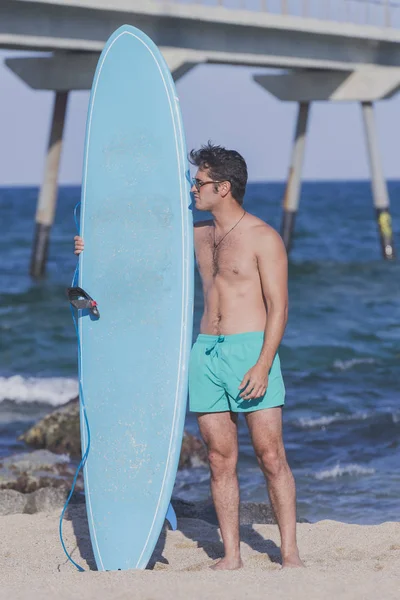 Surfista con la sua tavola da surf blu — Foto Stock