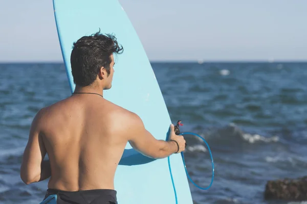Surfista sosteniendo su tabla de surf azul — Foto de Stock