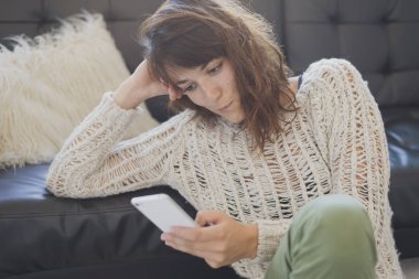 Cep telefonu, salon üzerinde oturan bir neşeli kadın