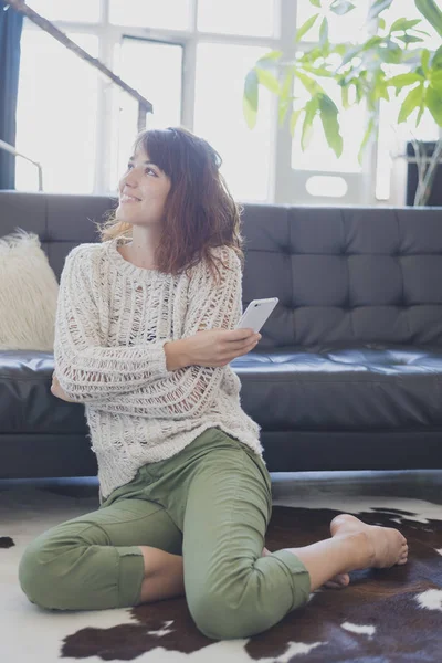 Cep telefonu, salon üzerinde oturan bir neşeli kadın