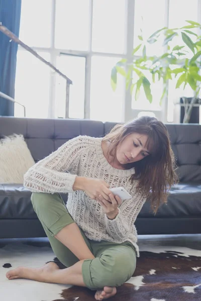 Mujer alegre hablando por teléfono móvil, sentada en la sala de estar — Foto de Stock