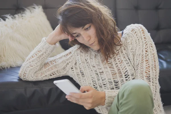 Cep telefonu, salon üzerinde oturan bir neşeli kadın