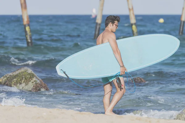 Surfista llevando su tabla de surf azul por detrás —  Fotos de Stock