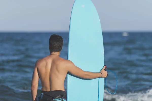 Surfeur portant sa planche de surf bleue — Photo
