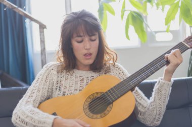 Gitar çalmak koltukta oturan güzel genç kadın