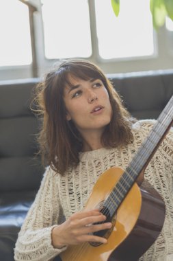Gitar çalmak koltukta oturan güzel genç kadın