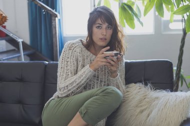 Kanepede, süre dört gözle ve gülümseyerek oturan bir kadın