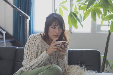 Kanepede, süre dört gözle ve gülümseyerek oturan bir kadın