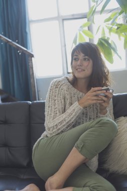 Kanepede, süre dört gözle ve gülümseyerek oturan bir kadın