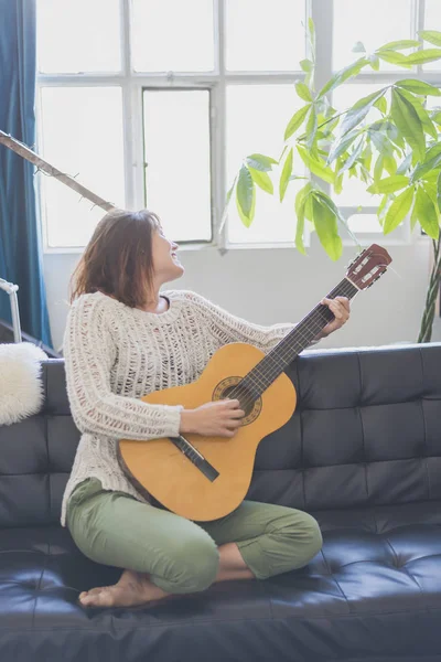 Gitar çalmak koltukta oturan güzel genç kadın