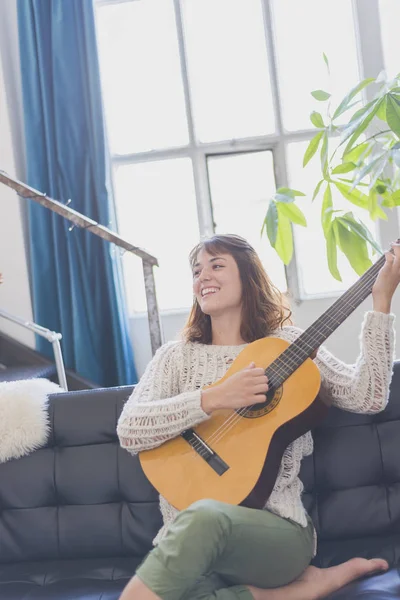 Gitar çalmak koltukta oturan güzel genç kadın